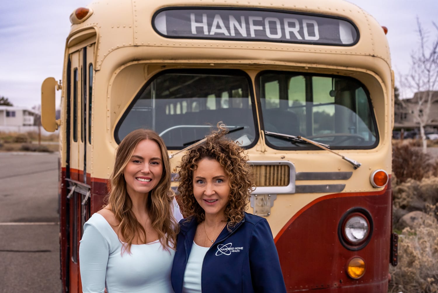 Hanford Home Health_Website Shoot_02.2025-00862 owners of Hanford Home Health standing in front of the Hanford bus